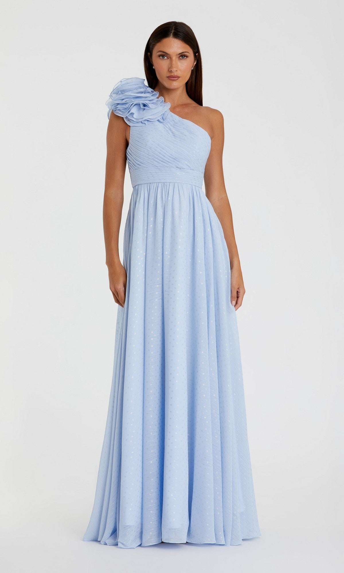 A woman wears the Mac Duggal 49536—an elegant, floor-length, light blue one-shoulder formal dress with a large shoulder floral detail and subtle dotted pattern—standing against a plain background.